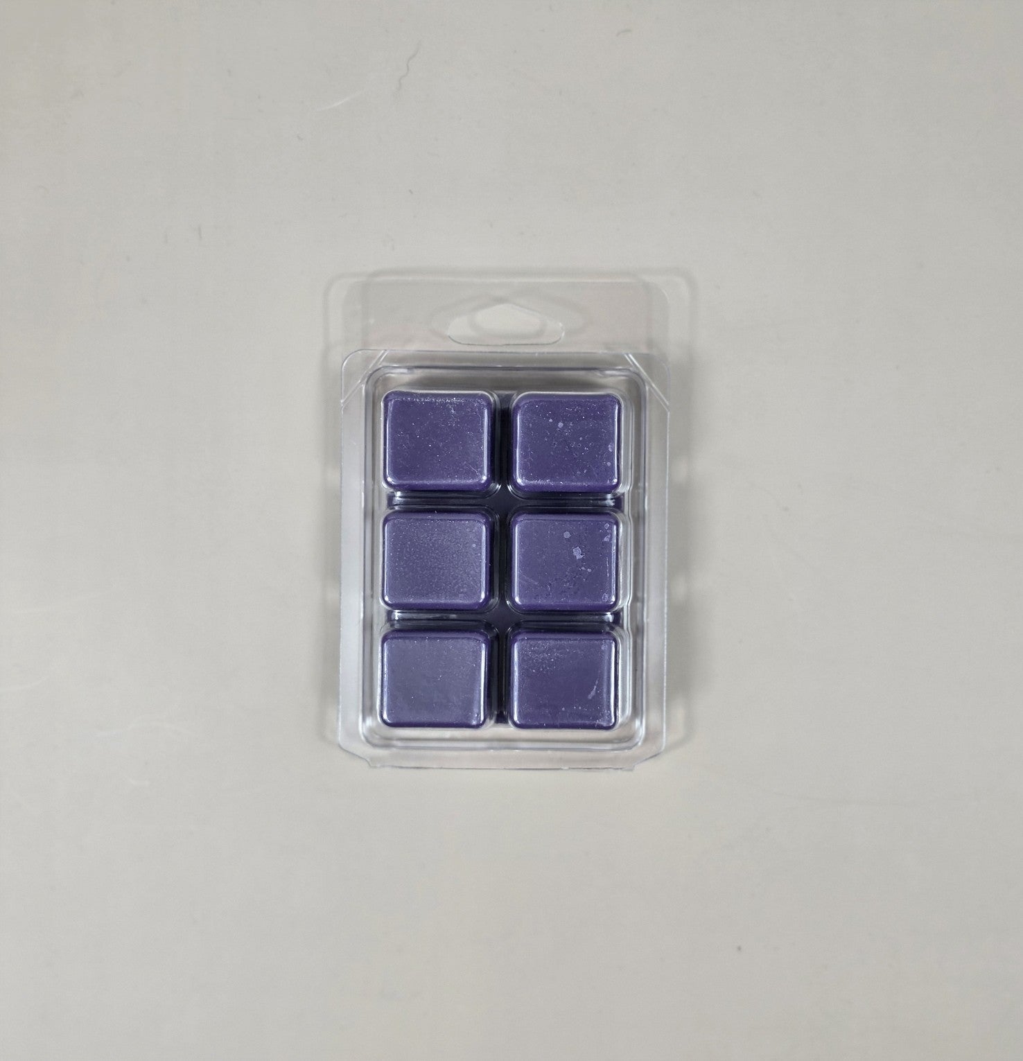 Pack of six purple wax melts in clear packaging on a light gray background