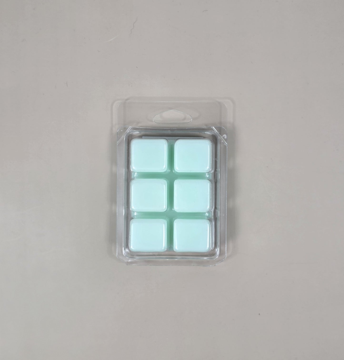 Pack of light blue wax melts in clear packaging on a gray background