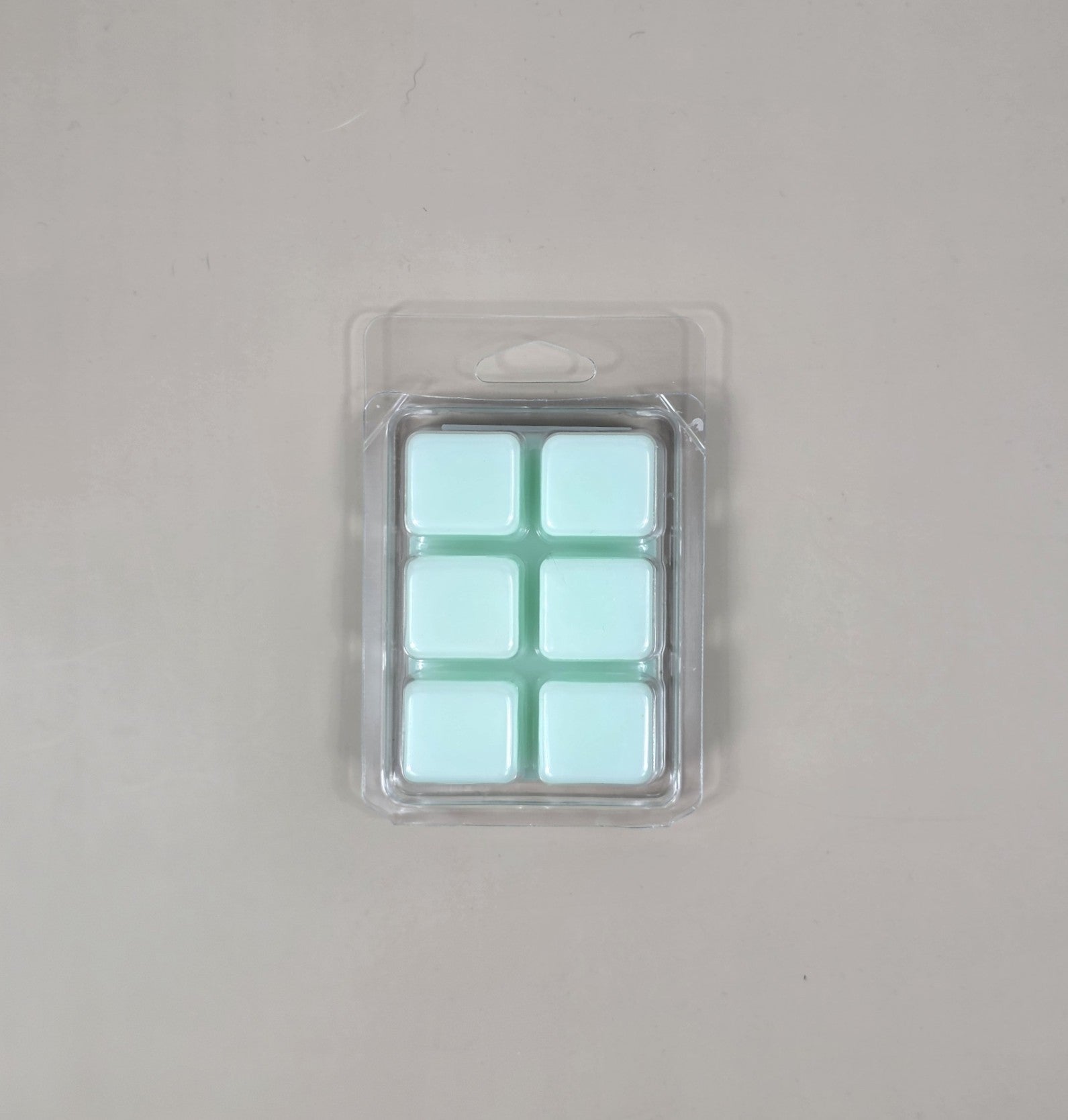 Pack of light blue wax melts in clear packaging on a gray background