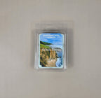 Packaged candle labeled 'Ocean Breeze' with a scenic design on a plain background