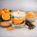 Orange Sherbet soy wax candle in a white frosted glass jar with a wooden lid, lit single wick, surrounded by fresh oranges, orange sherbet ice cream, and vanilla beans.
