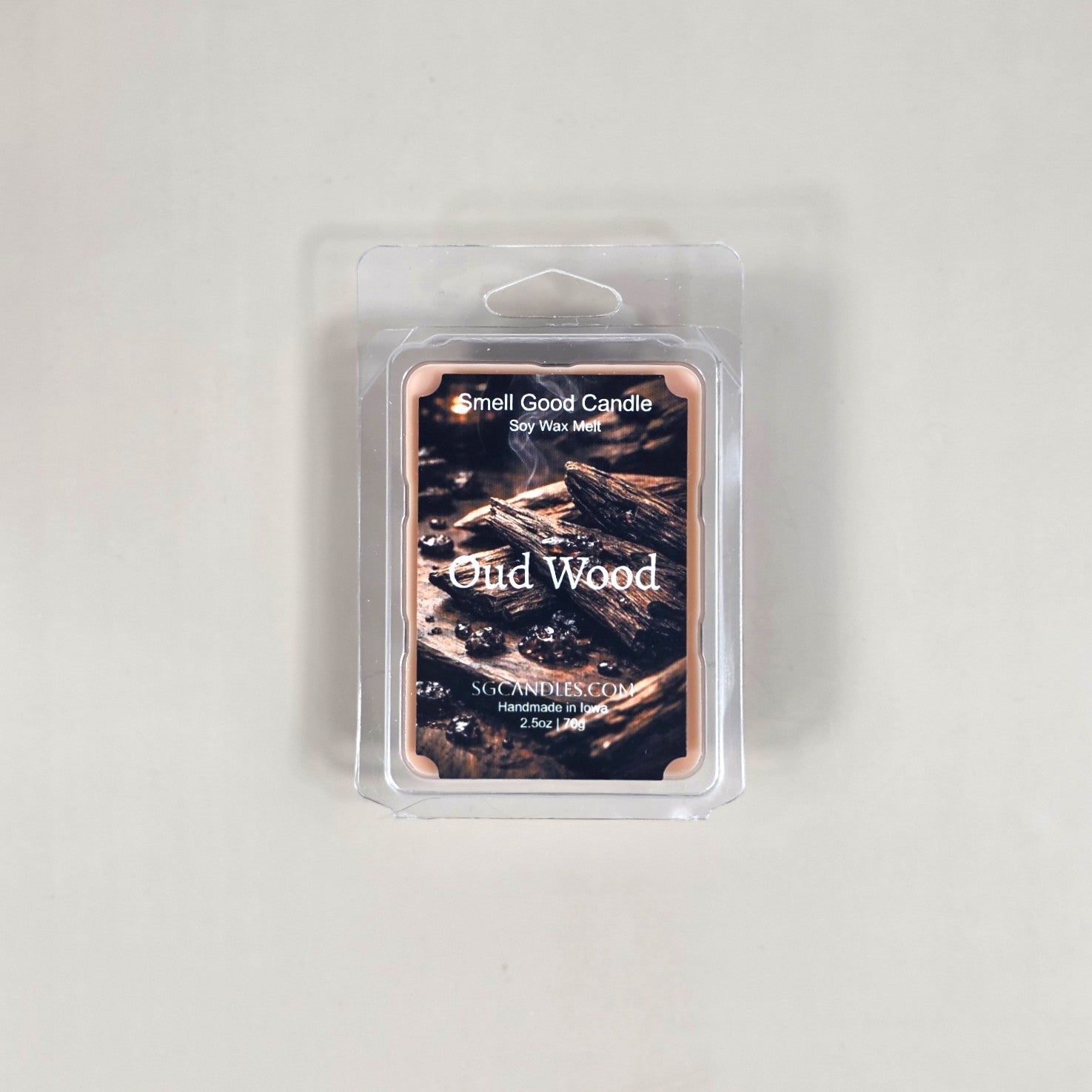Labeled Oud Wood soy wax melt in a 2.5oz clamshell with a sleek, minimalist label featuring a luxury wood texture design.