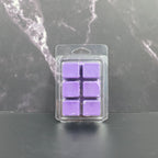 Pack of six purple wax melts in clear packaging on a dark marble surface