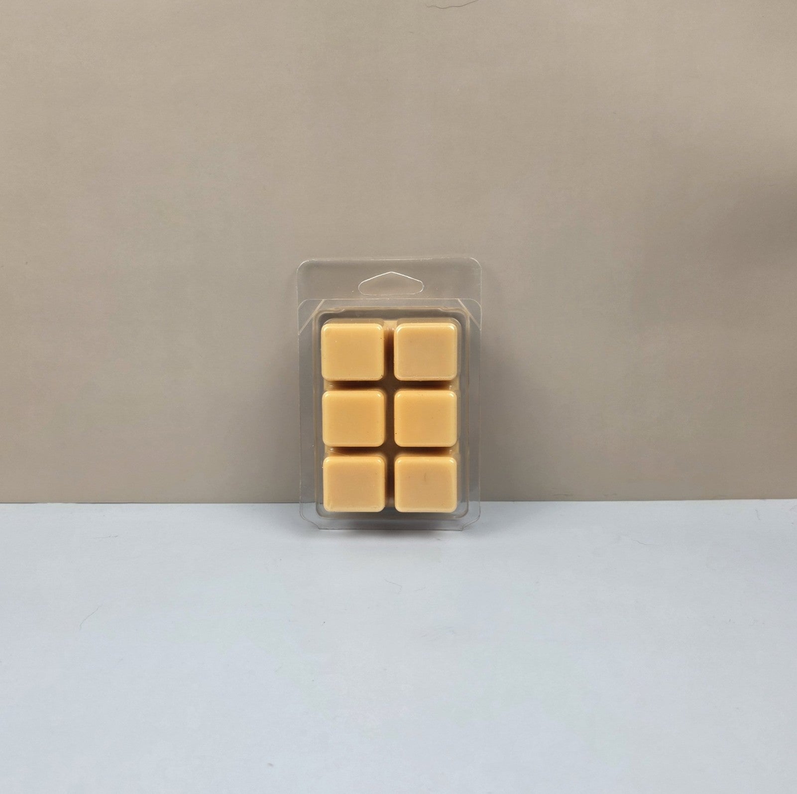 Pack of eight square wax melts in clear packaging on a beige background