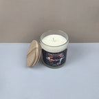 Candle in a glass jar with a wooden lid on a white surface against a beige background