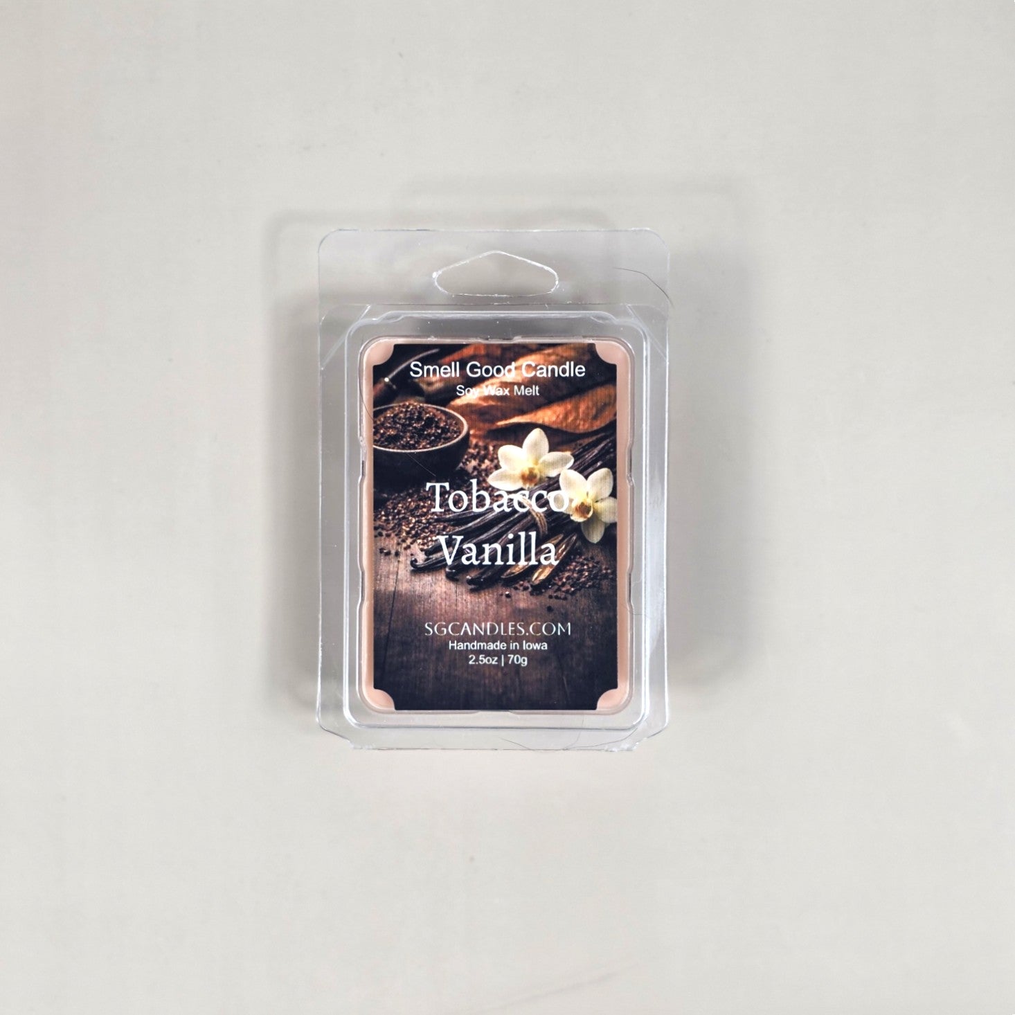 Labeled Tobacco Vanilla soy wax melt in a 2.5oz clamshell with a luxury label depicting a glass of bourbon and dried tobacco leaves.