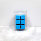 Earth-toned wax melt cubes beside moss, bark, and sandalwood
