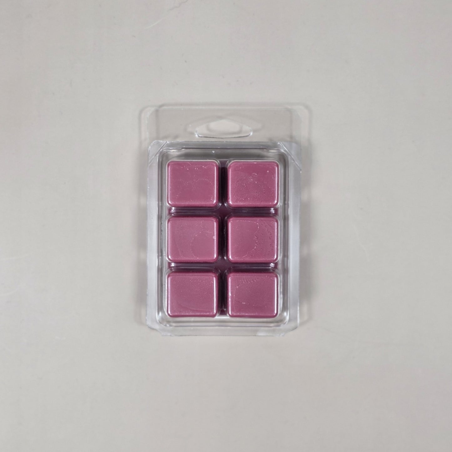 Pack of six pink wax melts in a clear plastic packaging on a light gray background