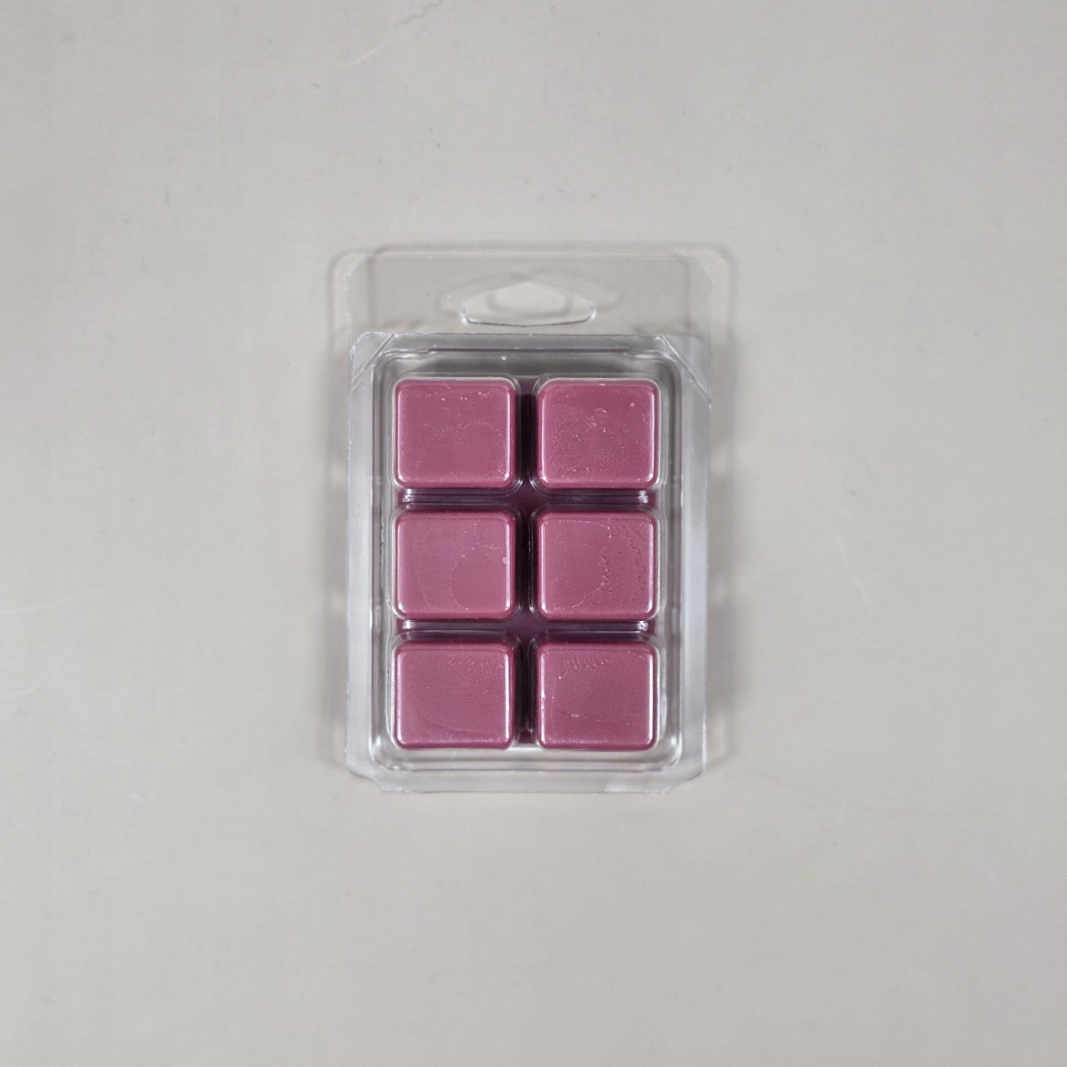Pack of six pink wax melts in a clear plastic packaging on a light gray background