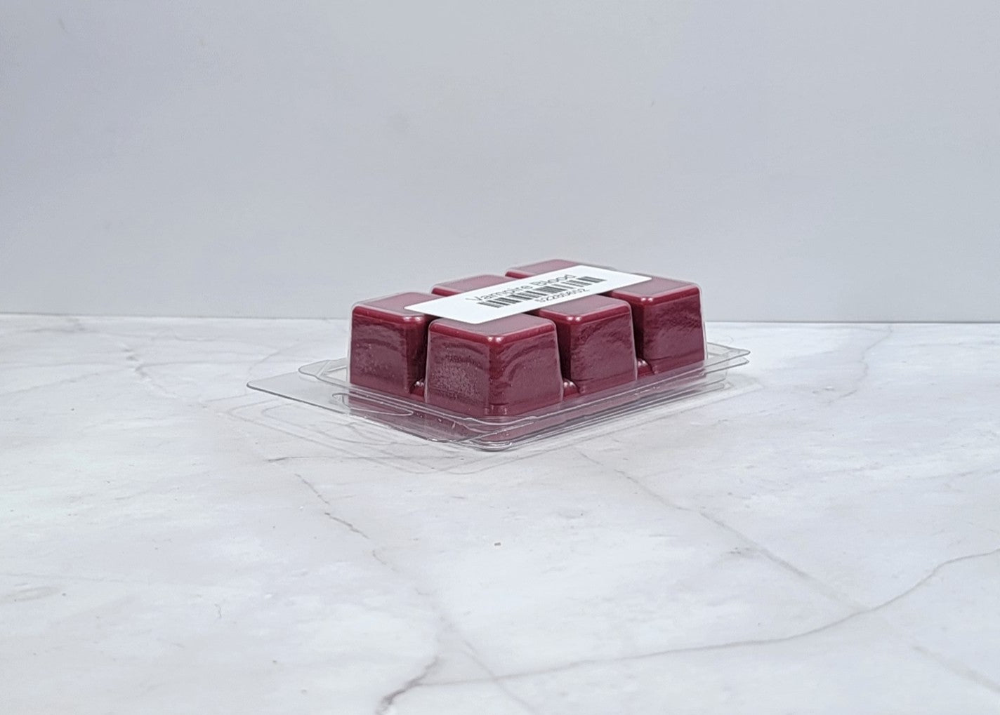 Dark-themed wax melt with berries and plum on a velvet backdrop