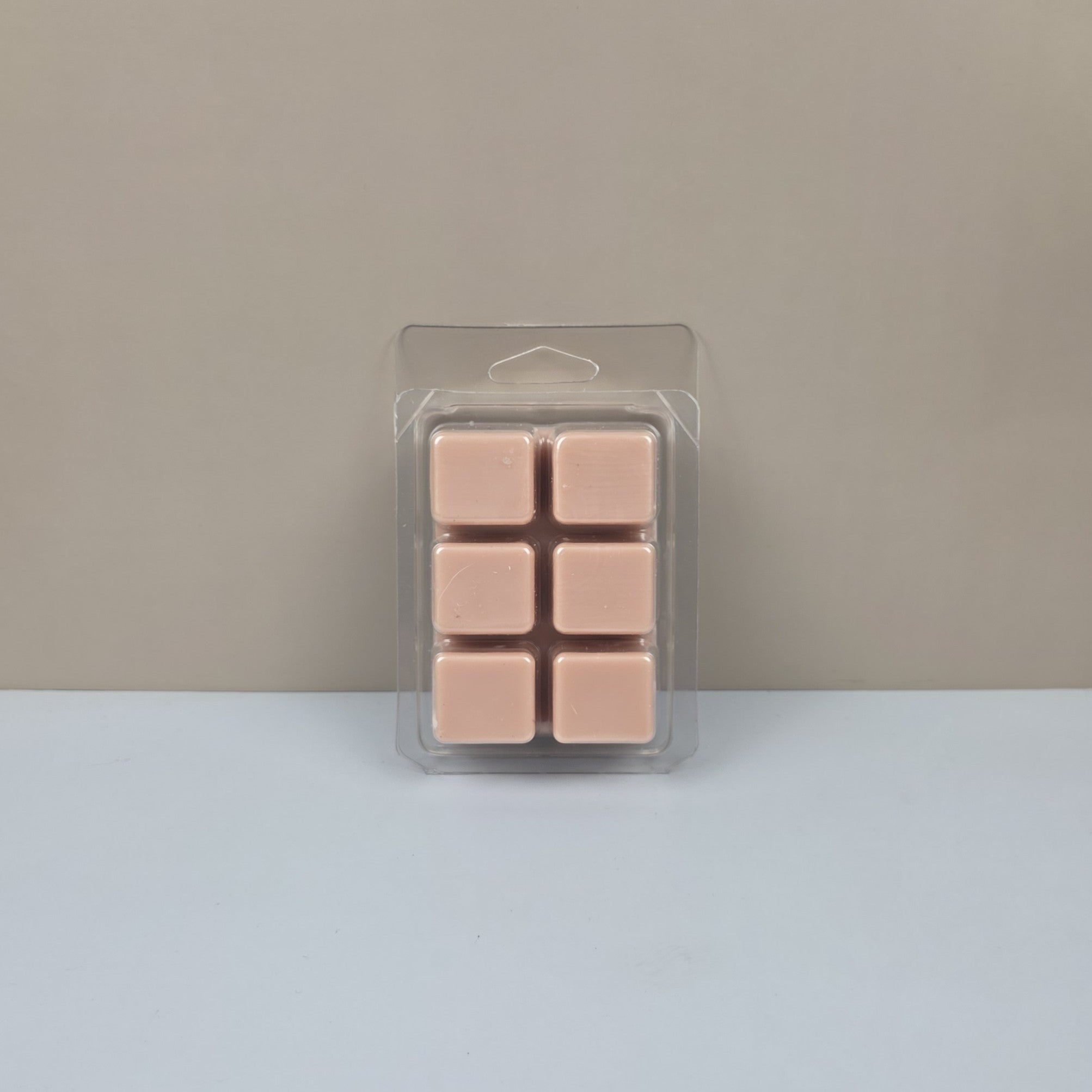 Pack of pink wax melts in clear packaging on a gray background