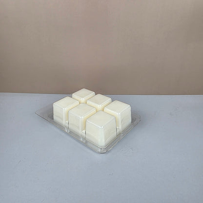 Pack of white wax melts in a clear plastic packaging against a gray background