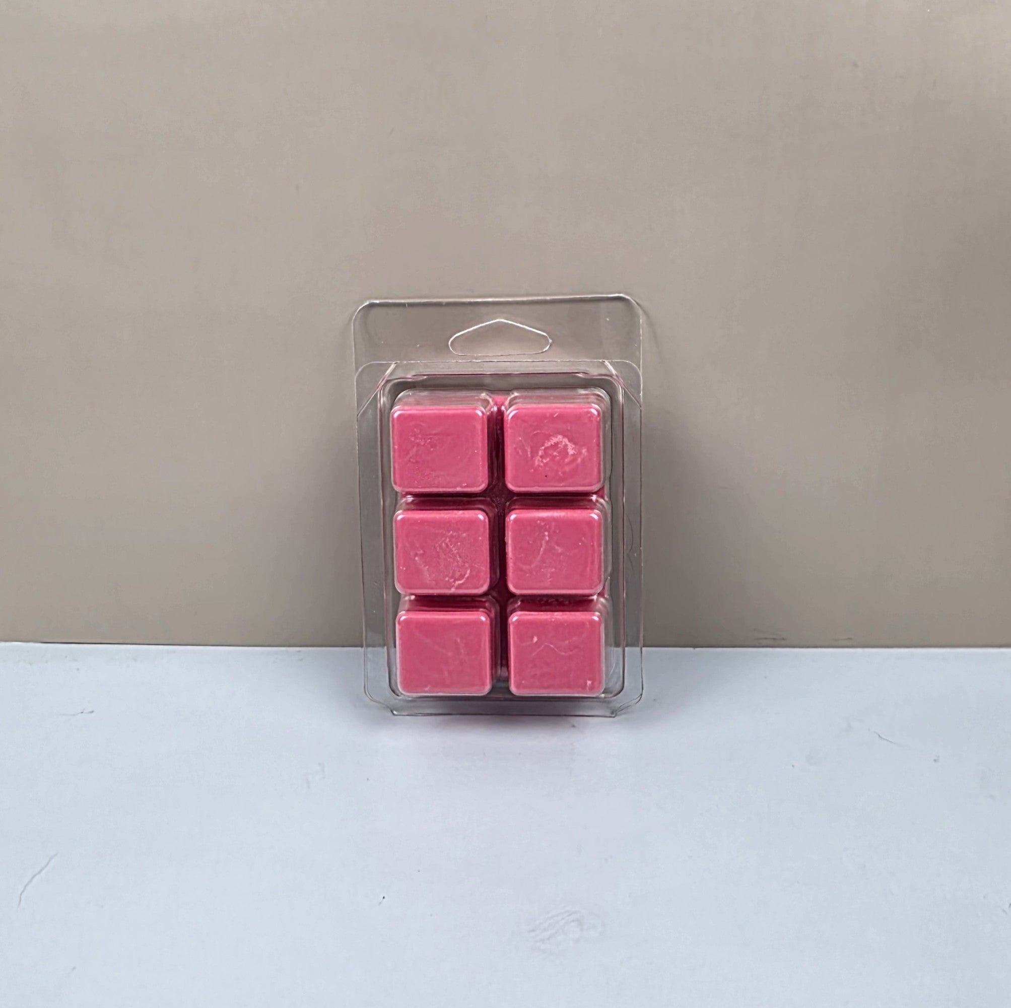 Pack of pink wax melts in clear packaging on a light gray background